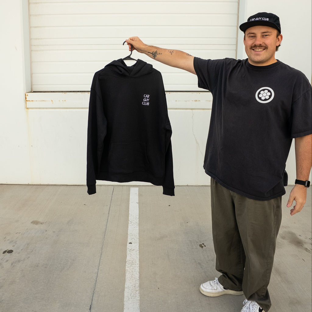 Man holding a black sweatshirt in front of a white garage door
