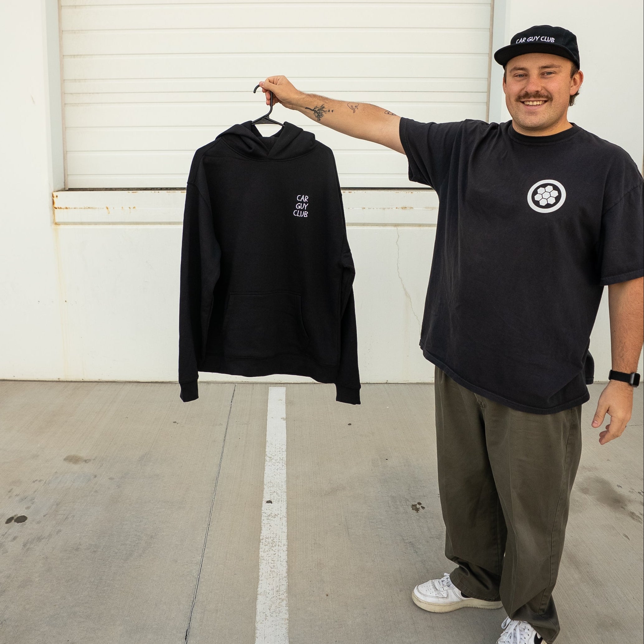Man holding a black sweatshirt in front of a white garage door