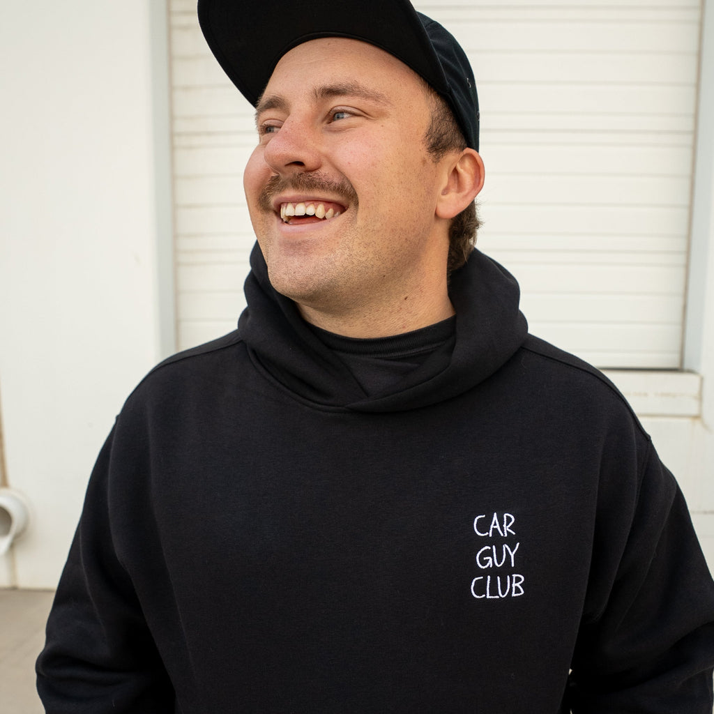 Man wearing a black hoodie with 'Car Guy Club' text, standing against a white background.